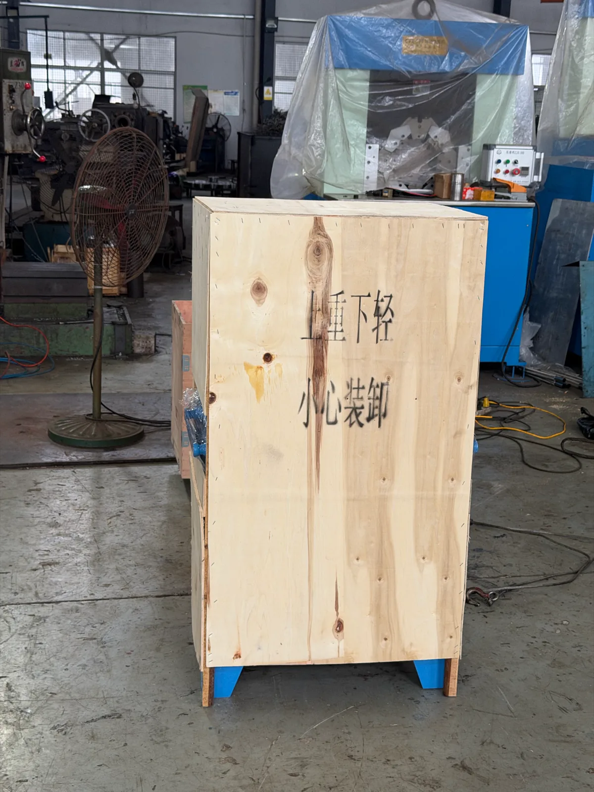 木箱正面写有“重心下移 / 小心装卸”提示