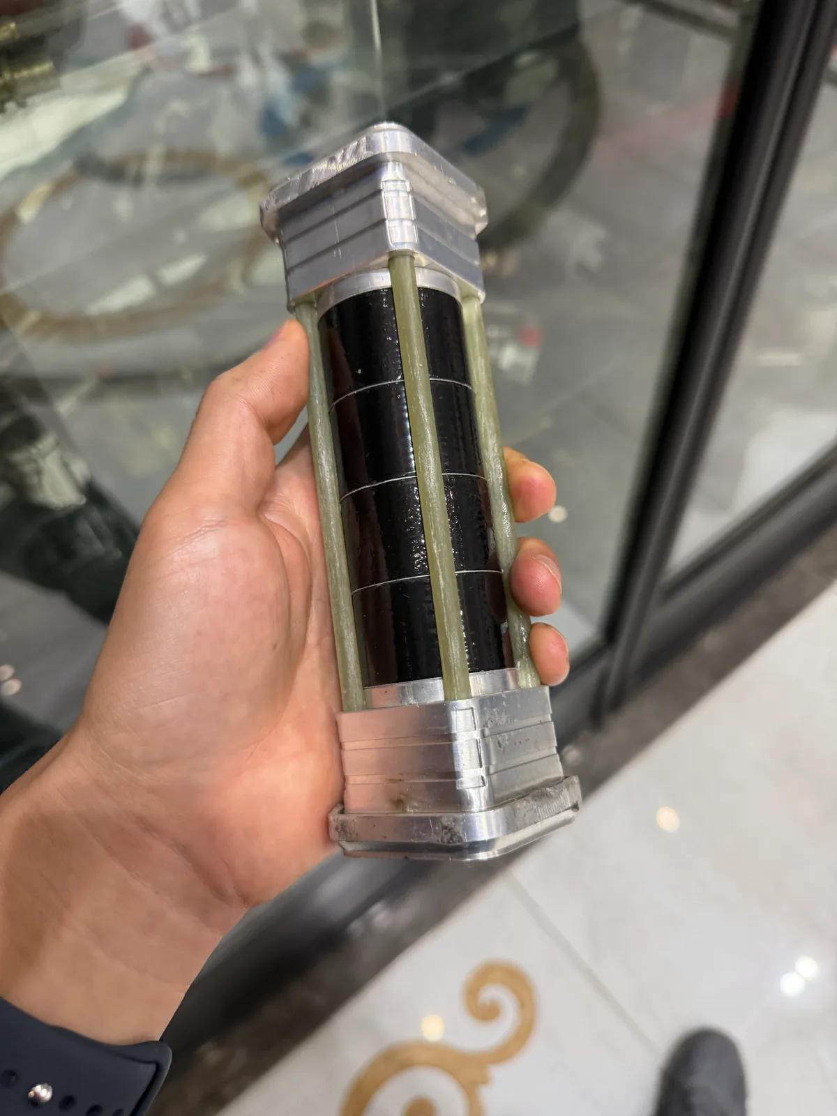 手持透明封装的剖开展示件,内部黑色管体与纵向增强层可见
