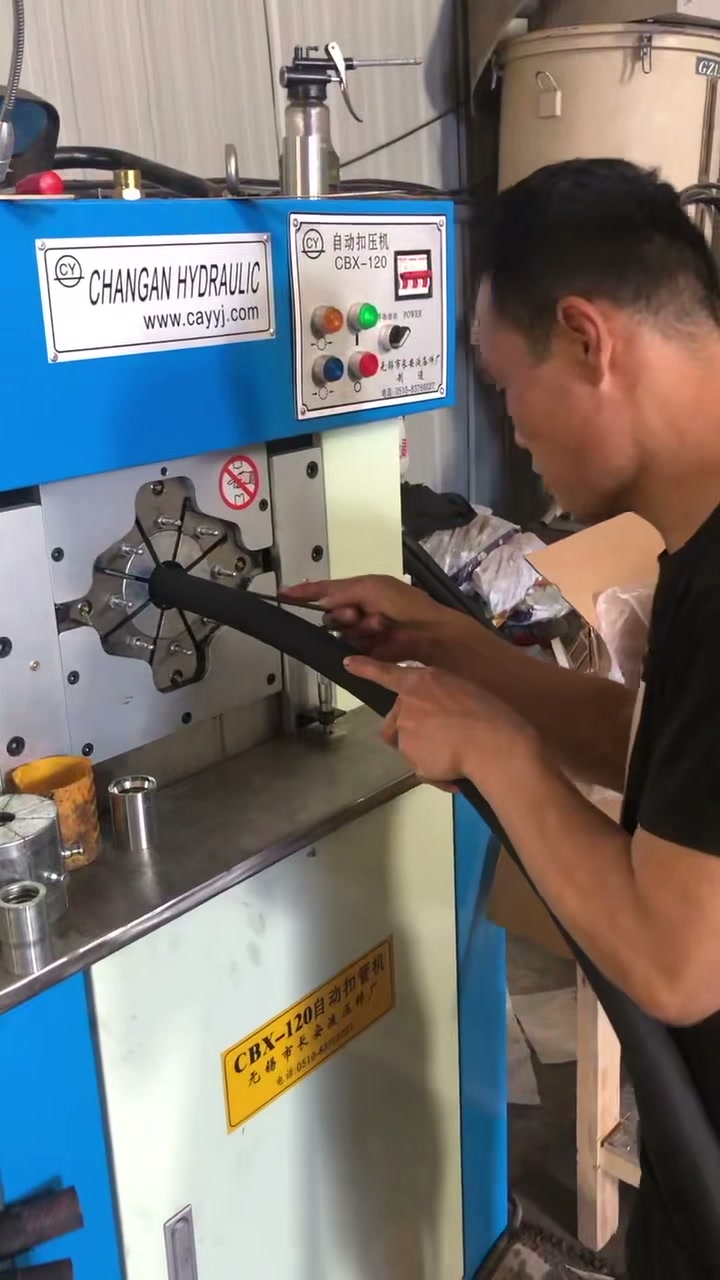工人将胶管送入蓝白扣压机，连续完成锁管动作（视频封面）